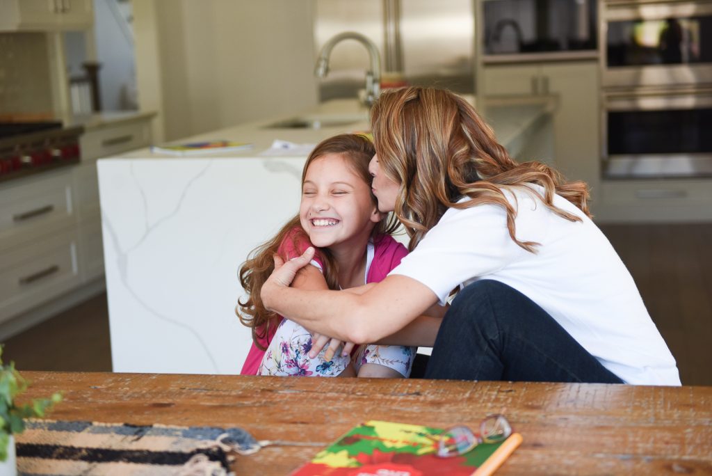 blonde haired mom hugging her daughter and give her a kiss on her forehead, parenting, prayer for your children, Renewed Mama Podcast